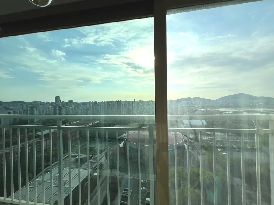 고층 아파트 발코니 창문 열차단필름 시공 후 산과 도심 전망