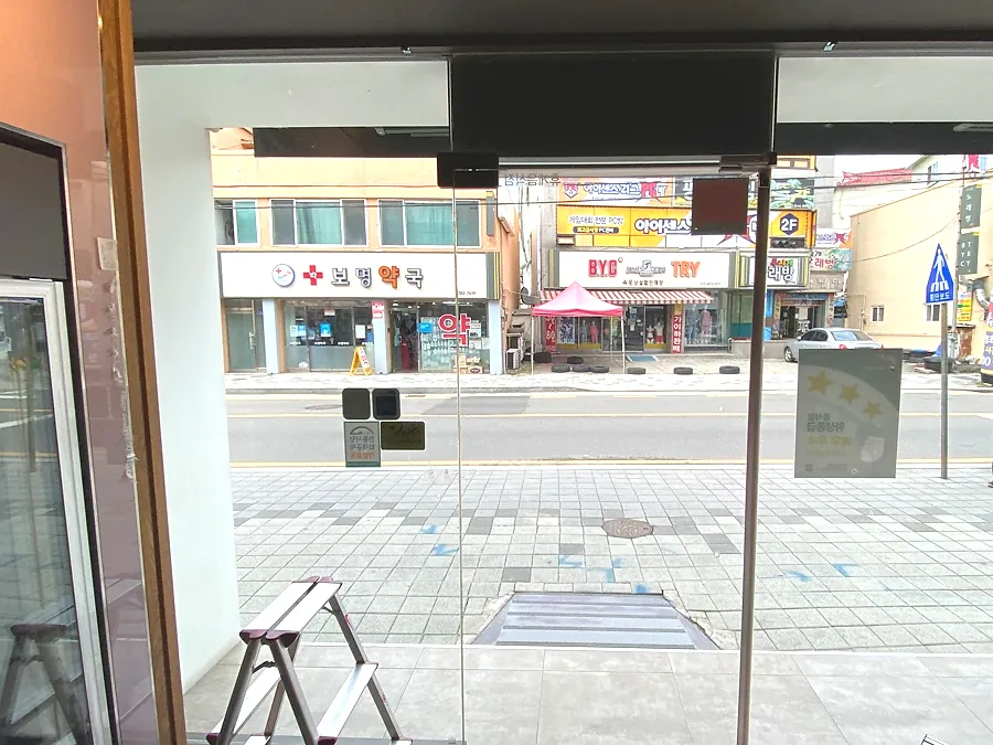 매장 전면 대형 통유리 상단 자외선차단필름 시공 후 도로변 전경이 담긴 클로즈업