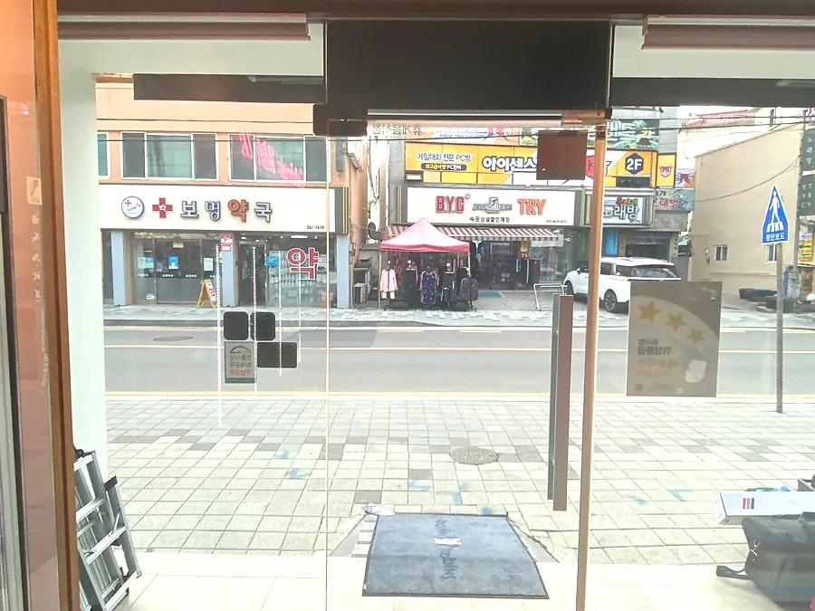 매장 통유리 너머 거리 풍경이 비치는 자외선차단필름 시공 완료 모습