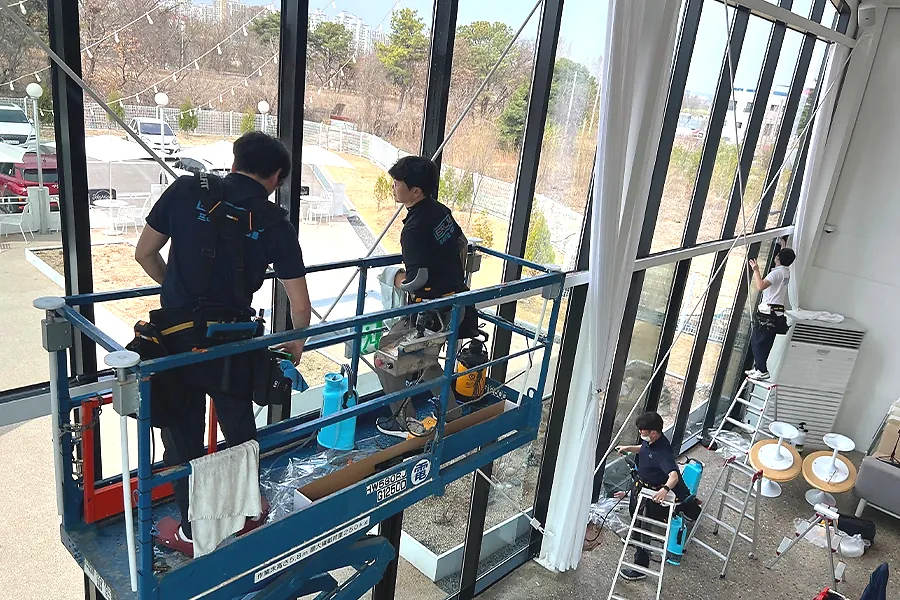 카페 매장 외부 대형 유리창 단열필름 시공 중 작업자 부착 클로즈업